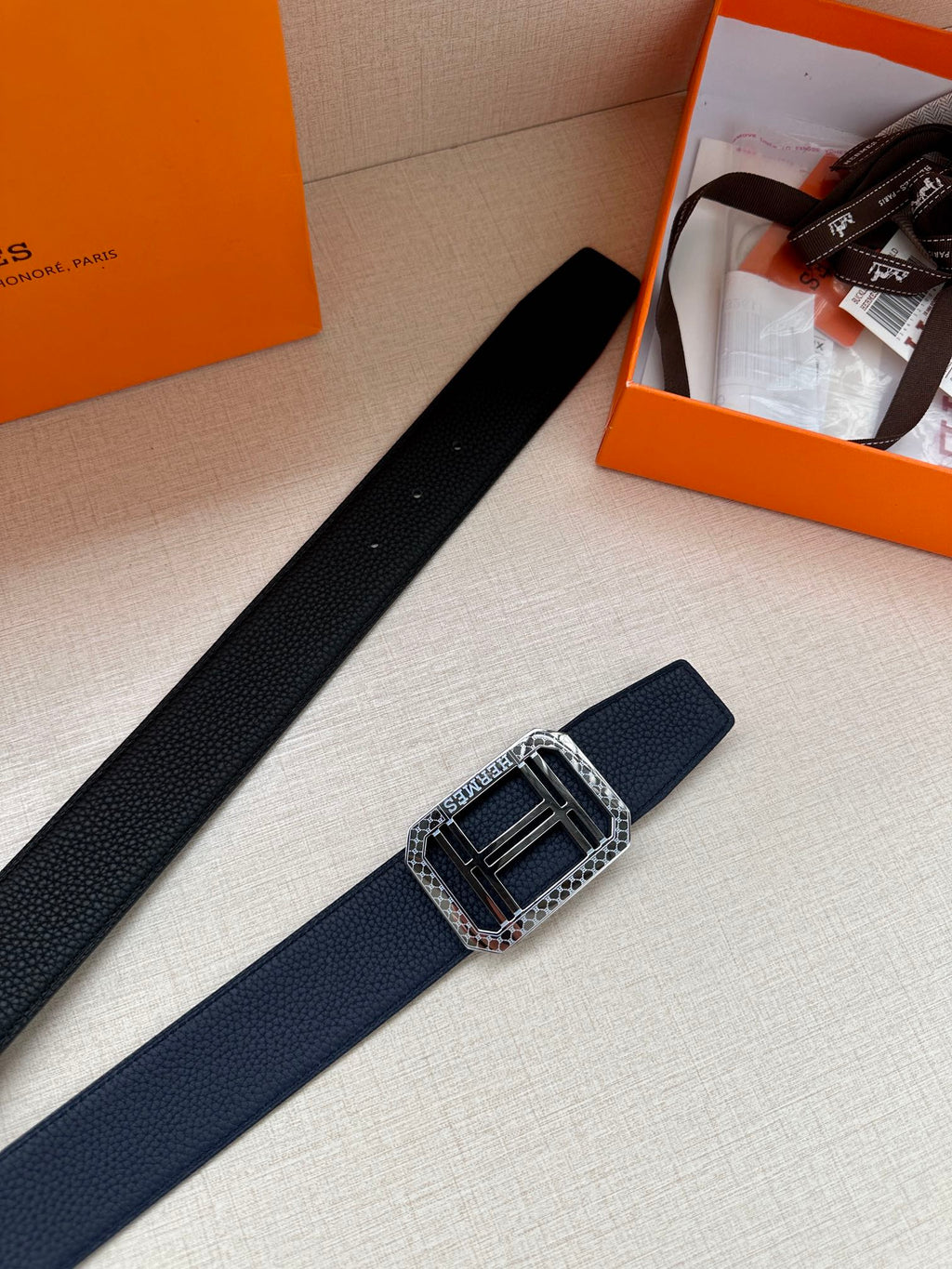 Navy leather belt with silver square buckle, shown angled on display