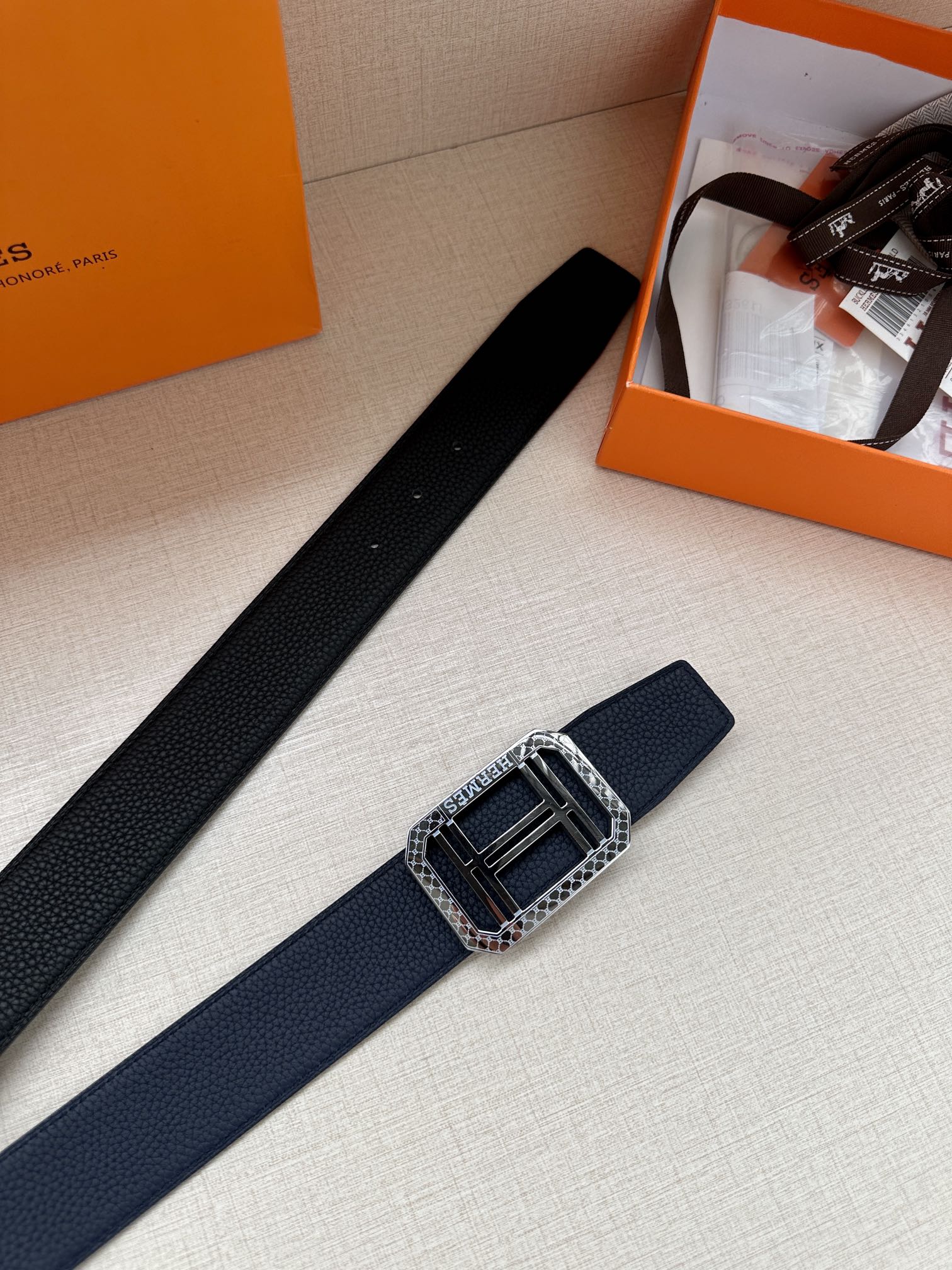 Navy leather belt with silver square buckle, shown angled on display