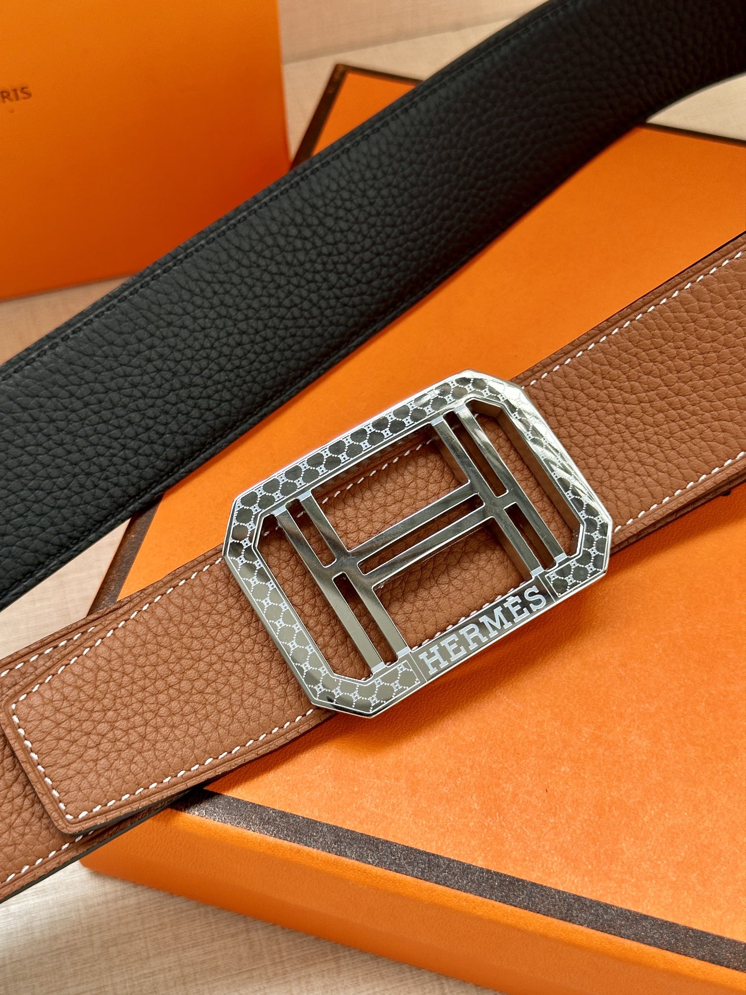 Brown leather belt with silver-toned H buckle and textured grain detail