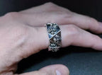 Silver-tone engraved statement ring held in hand, floral pattern detail