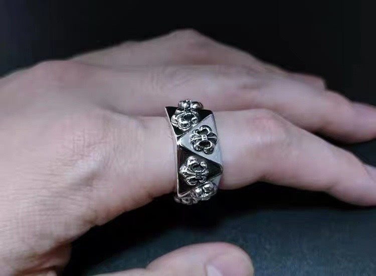 Silver-tone engraved statement ring held in hand, raised motif detail