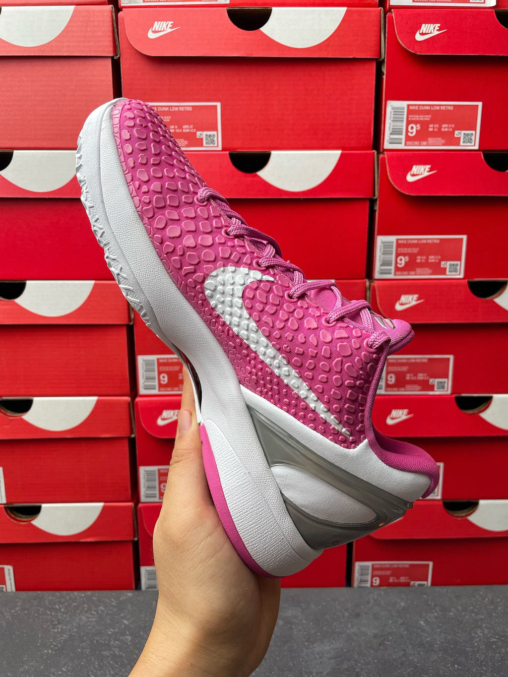 Pink basketball shoe with white swoosh and gray sole, angled side view.