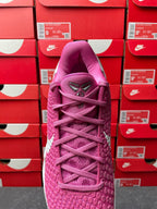 Pink basketball shoe with purple laces and textured knit upper, front view.