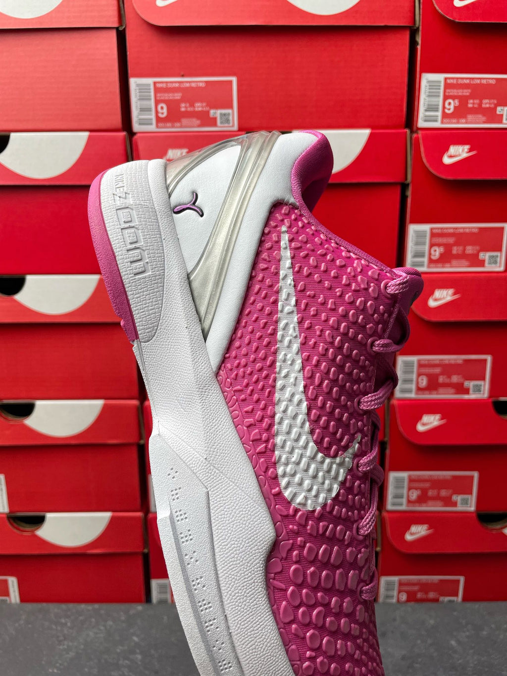 Pink and white basketball shoe showing textured side panel and gray outsole.