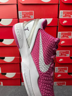 Pink and white basketball shoe showing textured side panel and gray outsole.