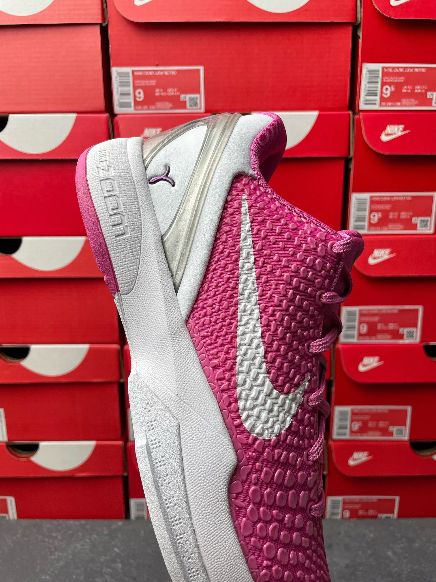 Pink and white basketball shoe showing textured side panel and gray outsole.