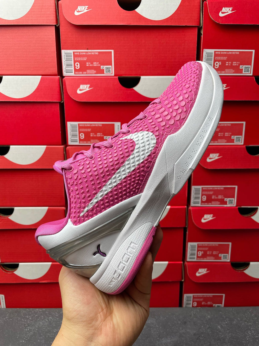 Pink basketball shoe with white side swoosh and gray outsole, angled view.