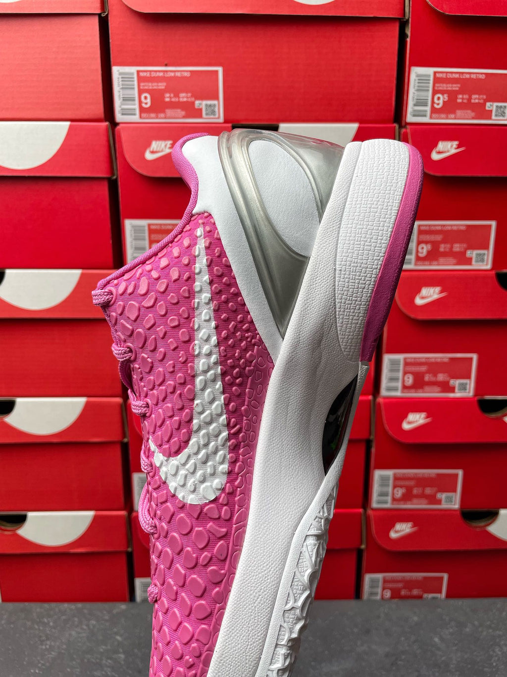 Pink basketball shoe with white outsole and raised textured upper, side-back view.