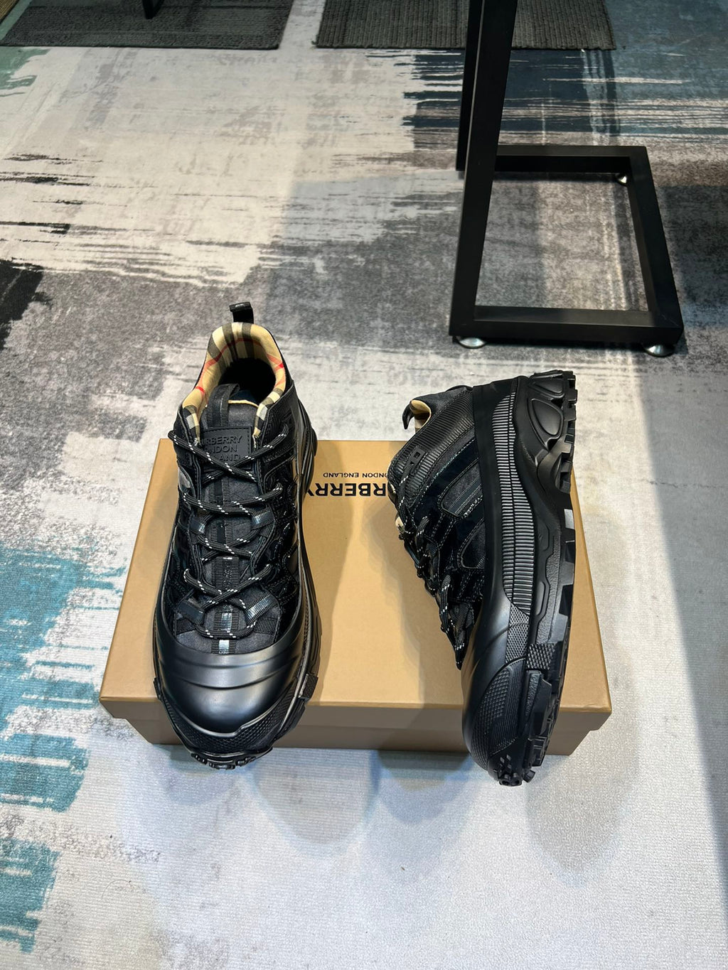 Burberry sneakers angled view on box, black uppers with thick traction sole