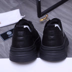 Black sneakers with heel tab and cushioned collar; thick rubber platform sole