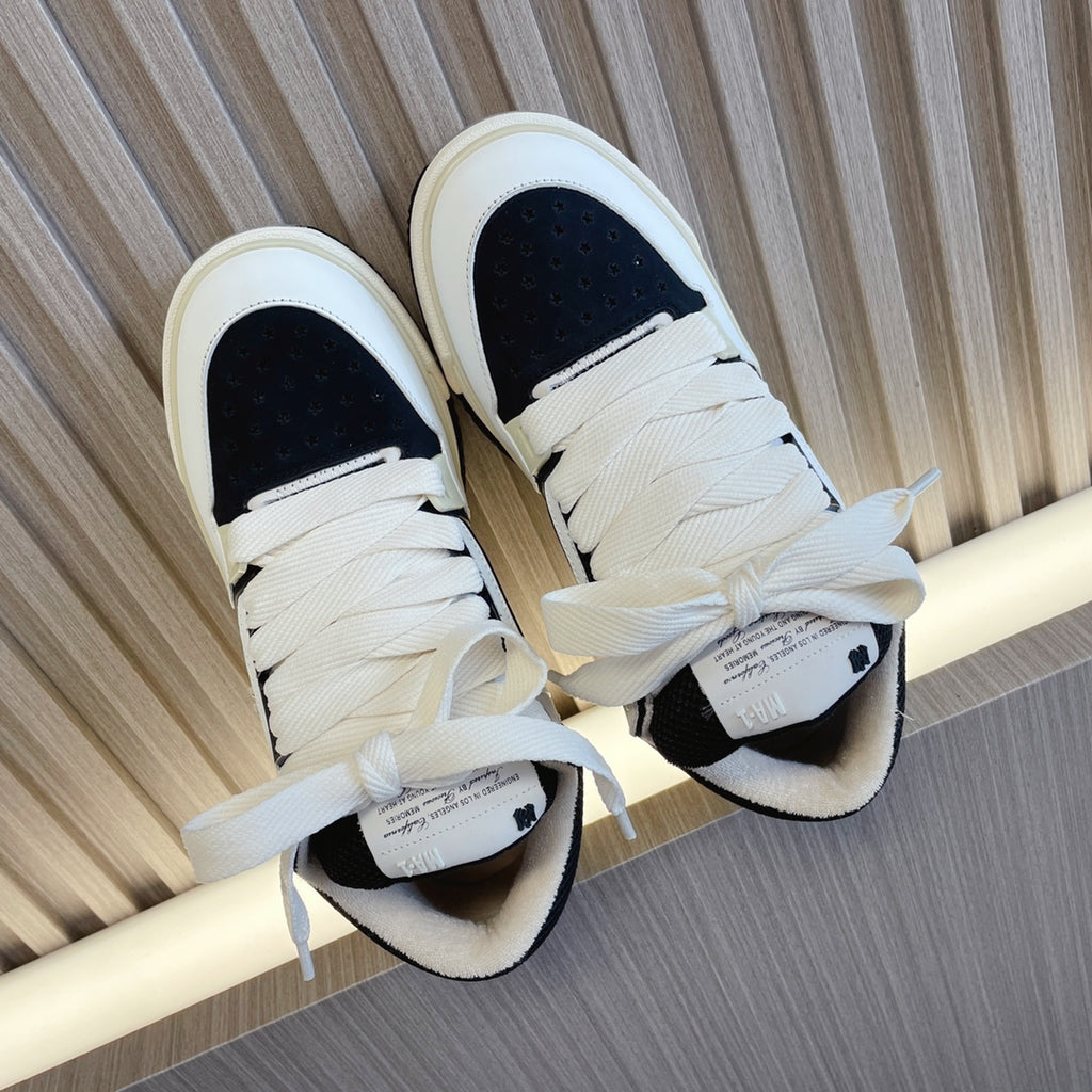 Amiri low-top sneakers with white upper and black panels, lace-up design