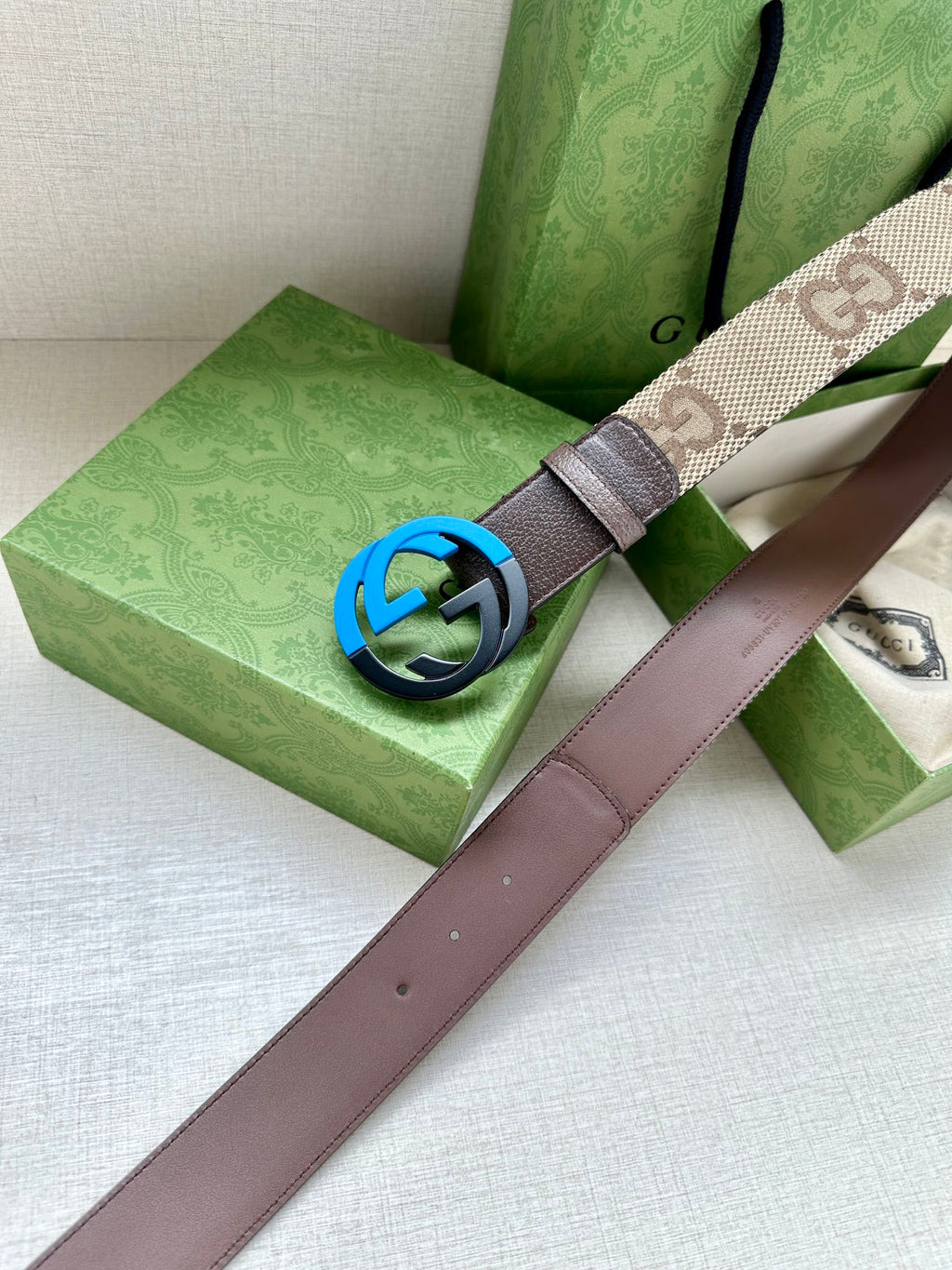 GG-pattern belt with dark blue interlocking G buckle and brown leather strap.