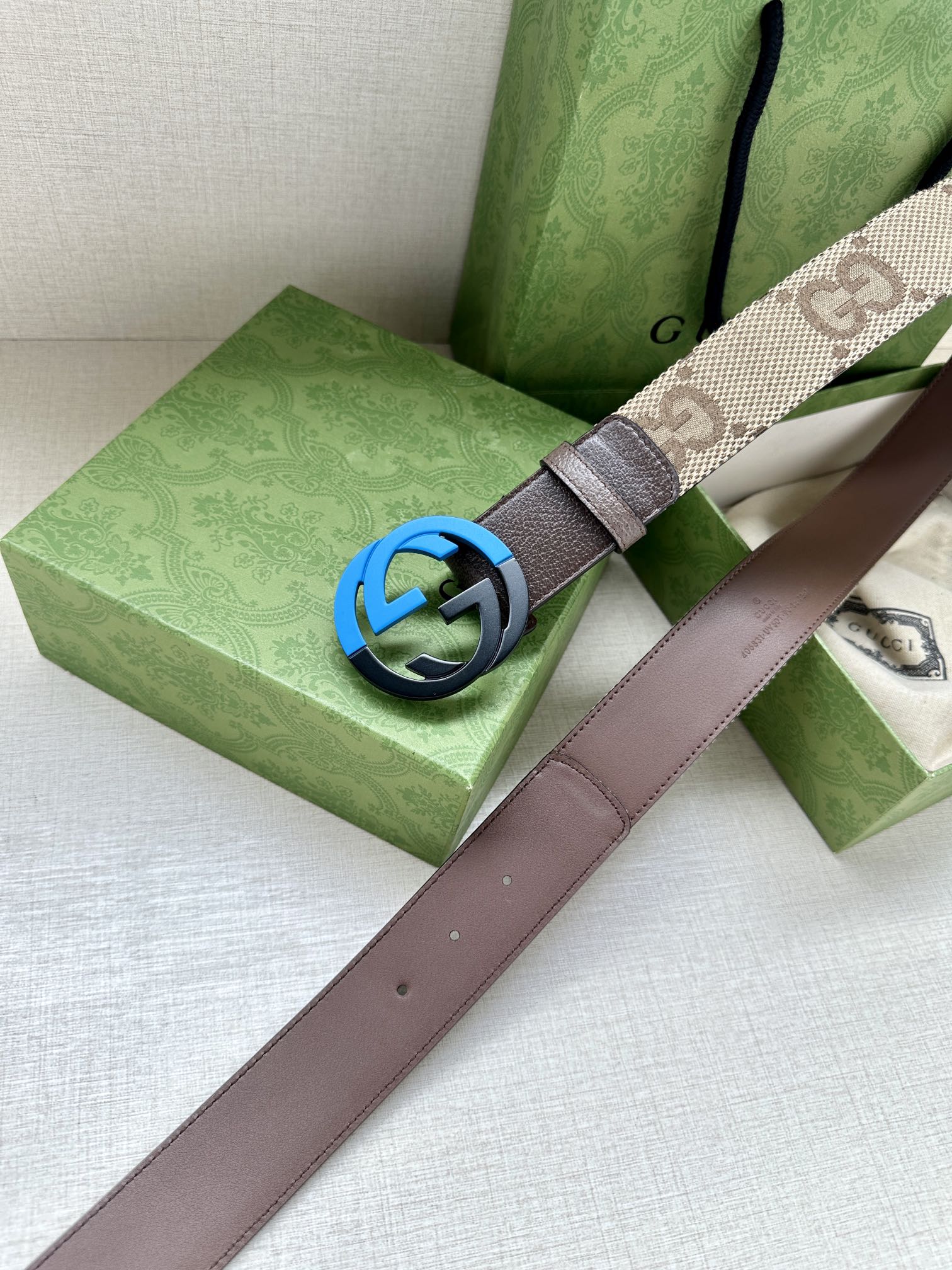 GG-pattern belt with dark blue interlocking G buckle and brown leather strap.
