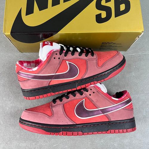 Pair of pink Nike SB Dunk Low sneakers with purple swoosh, black laces, and black sole