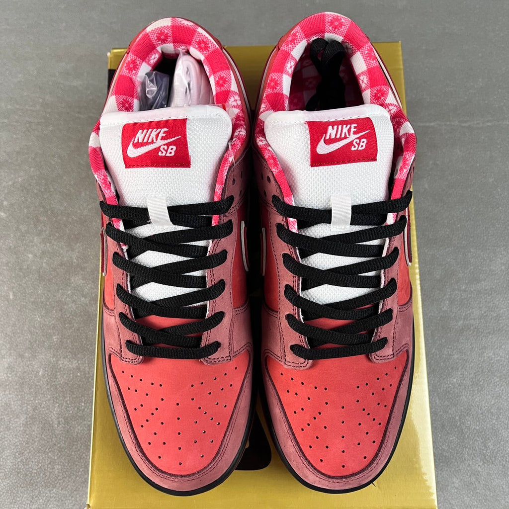 Pink Nike SB Dunk Low sneakers with white tongues labeled Nike SB and black laces