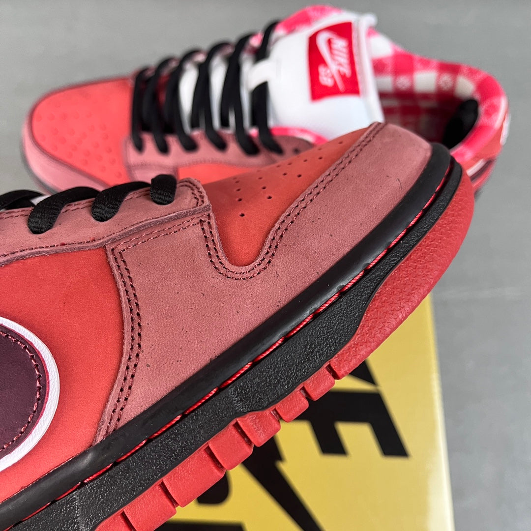 Nike SB Dunk Low sneaker with pink suede upper, purple swoosh, black outsole, red accents