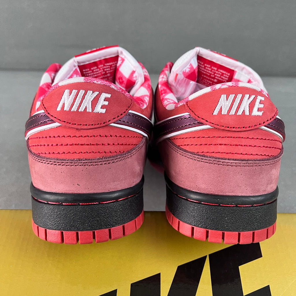 Pair of pink Nike SB Dunk Low sneakers with black heel tab and red striped sole