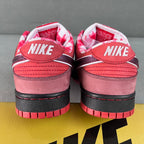Pair of pink Nike SB Dunk Low sneakers with black heel tab and red striped sole