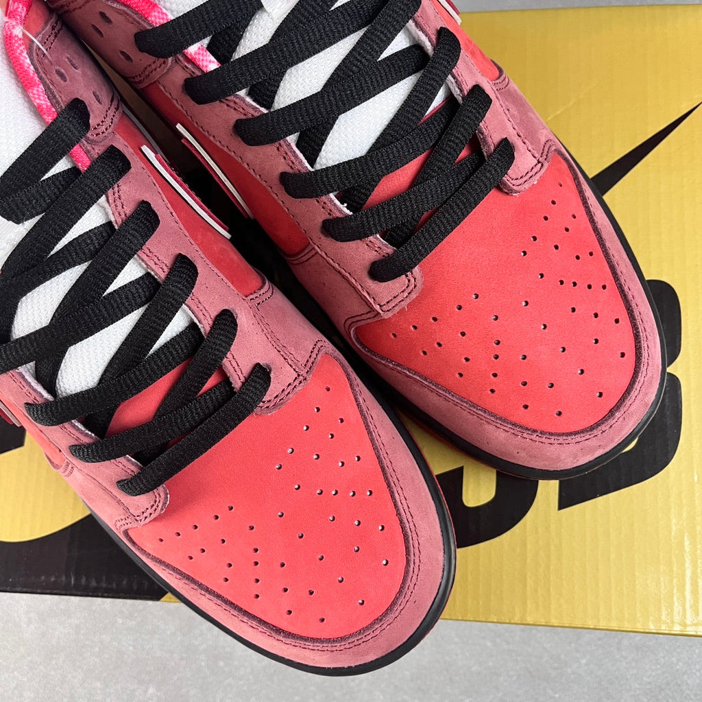 Pink Nike SB Dunk Low sneakers with black laces and perforated toe panels