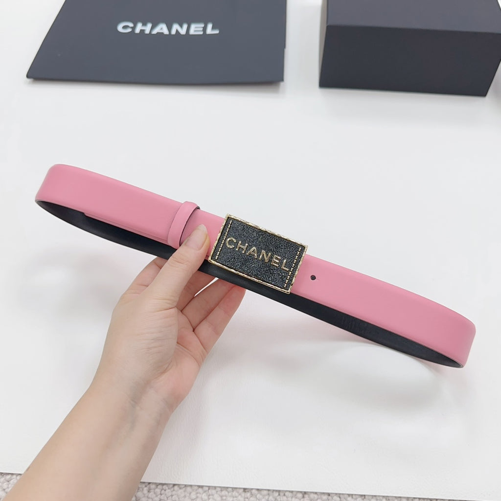 Chanel belt with pink strap and black CHANEL logo buckle, held in hand