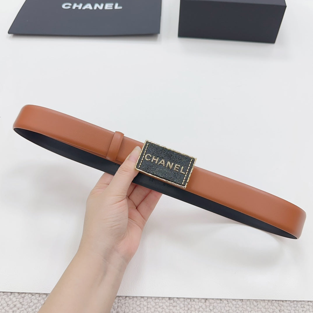 Chanel belt held in hand: tan leather strap with dark gold logo buckle