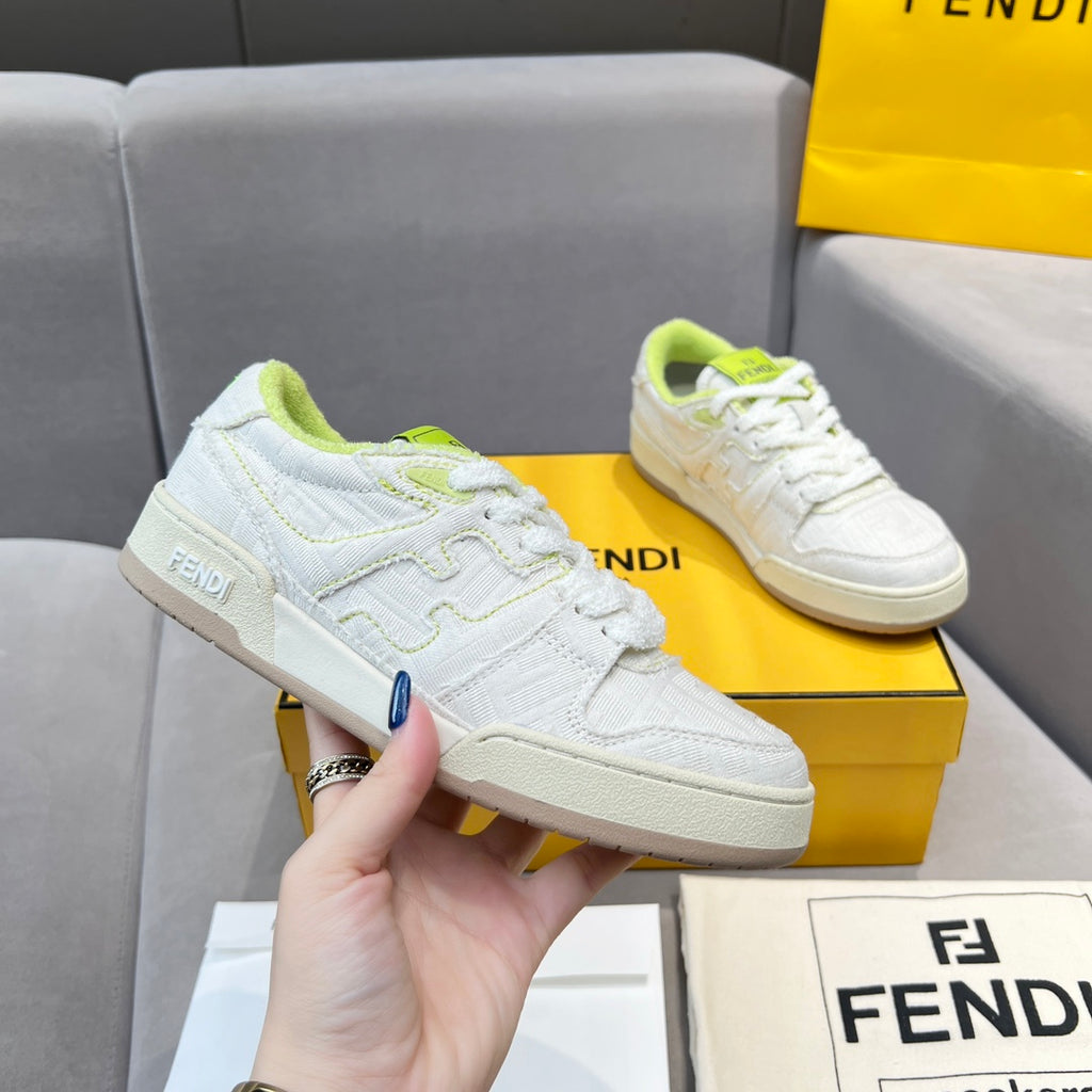 White unisex sneakers on box held by hand; neon green lace accents