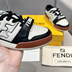 Close-up of lace-up sneakers with white upper, black strap details, and brown outsole
