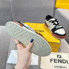 Outsole view of low-top sneakers with textured light gray sole and tan rubber accents