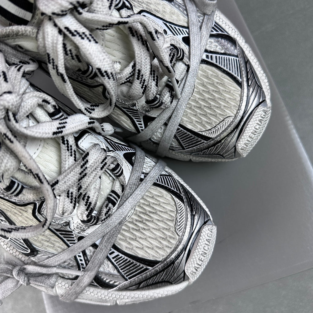 White lace-up sneakers with black trim, showing textured upper and sole tread