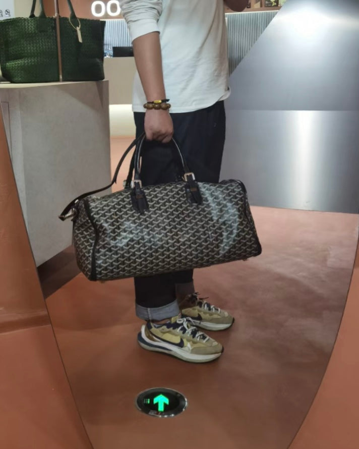 Patterned duffel bag with black leather handles and zip-top closure
