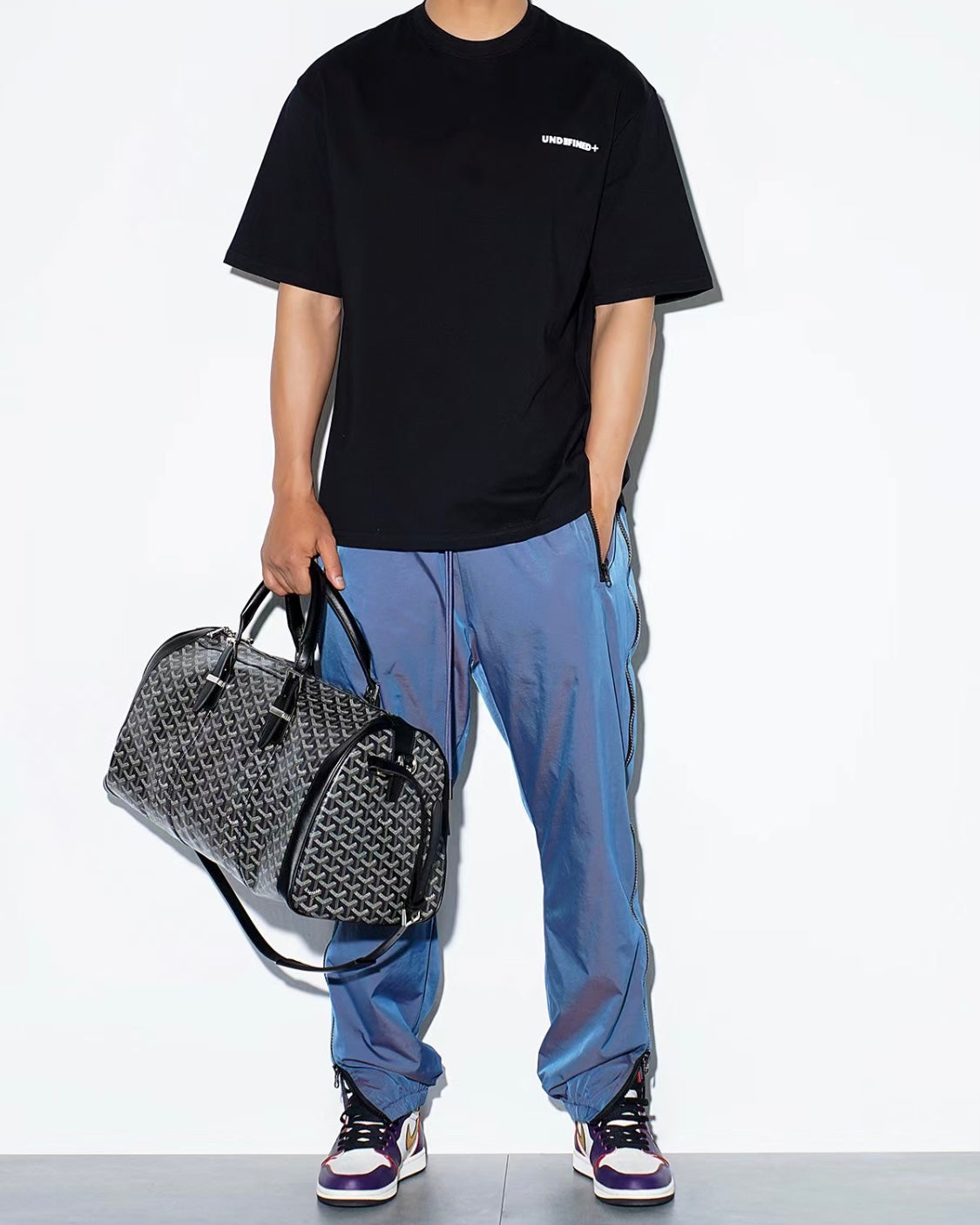 Patterned duffel bag with adjustable strap and dual top zippers, black leather trim