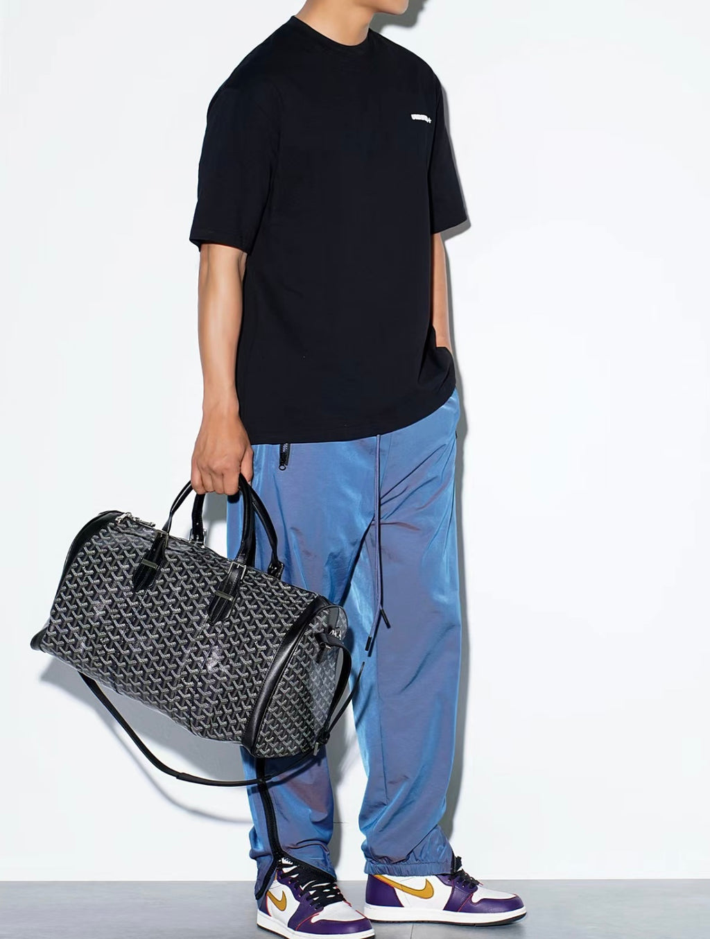 Patterned duffel bag with adjustable shoulder strap and black leather trim
