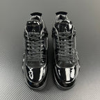 Pair of black Air Jordan 4 sneakers, glossy finish, lace-up with mesh overlays.