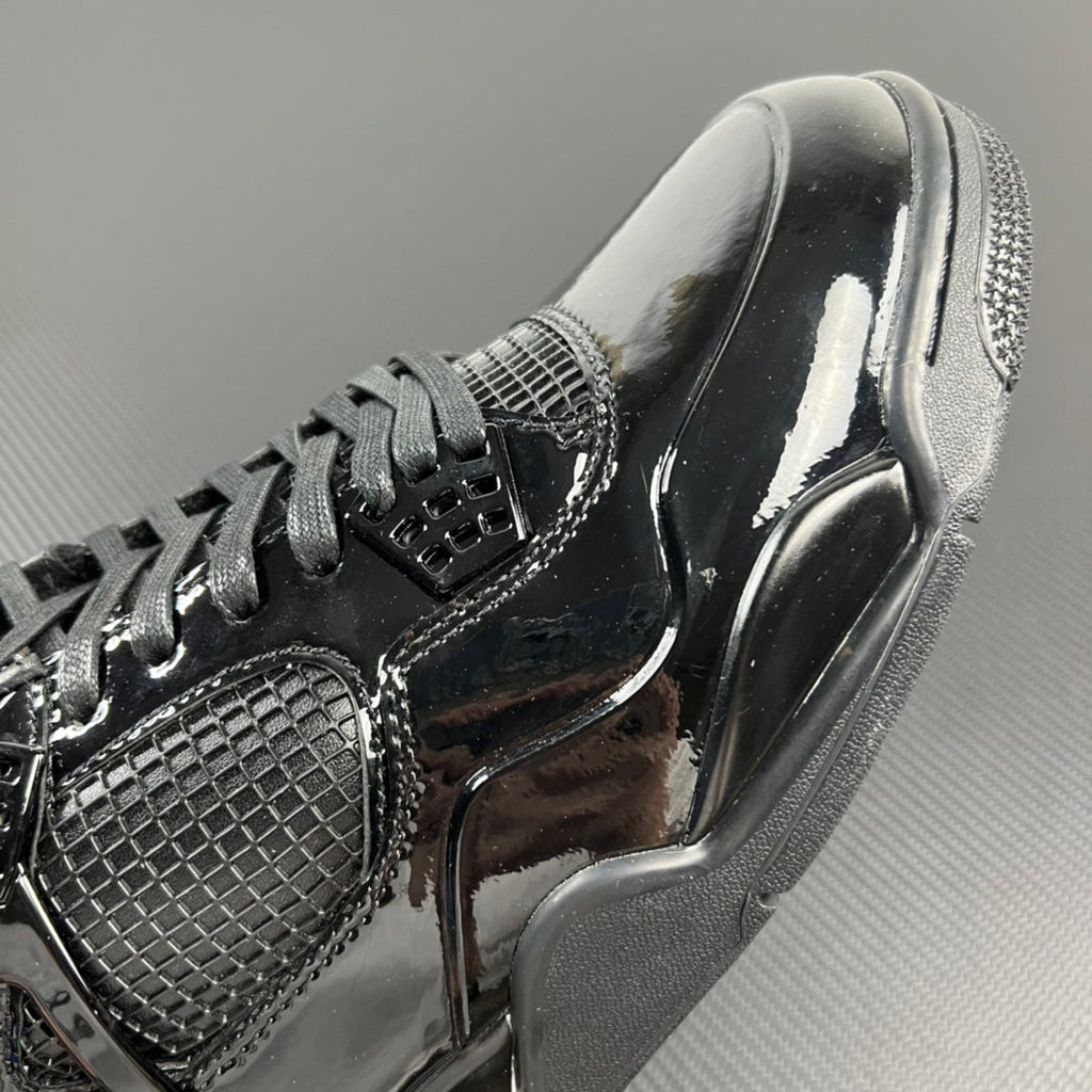 Black Air Jordan 4 upper close-up with mesh quarter panel and lace eyelets.