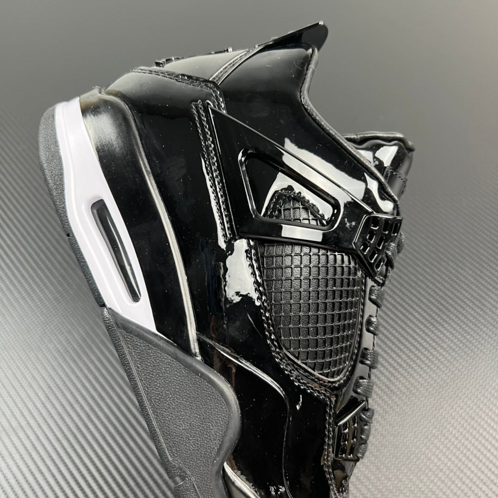Black Air Jordan 4 sneaker with side cage and white-striped midsole.