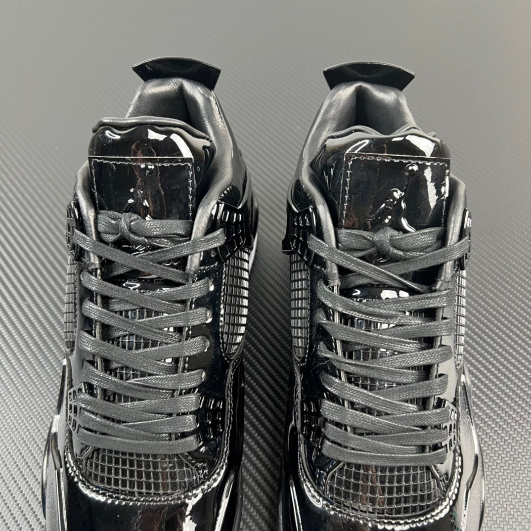 Two black Air Jordan 4 sneakers, lace-up uppers with mesh and patent panels.