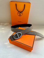 Gray leather belt with oval H buckle, belt laid flat with tail.