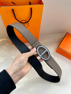 Gray leather belt with oval buckle, silver-tone border and dark center.