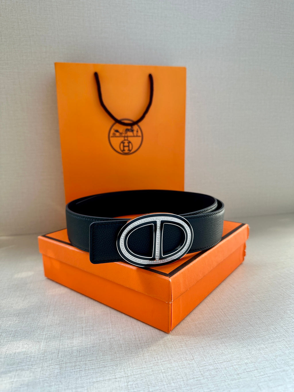 Black leather belt with silver-toned double “H” buckle centered on the dark strap.