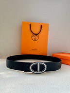 Black leather belt with silver-toned double “H” buckle on smooth strap.