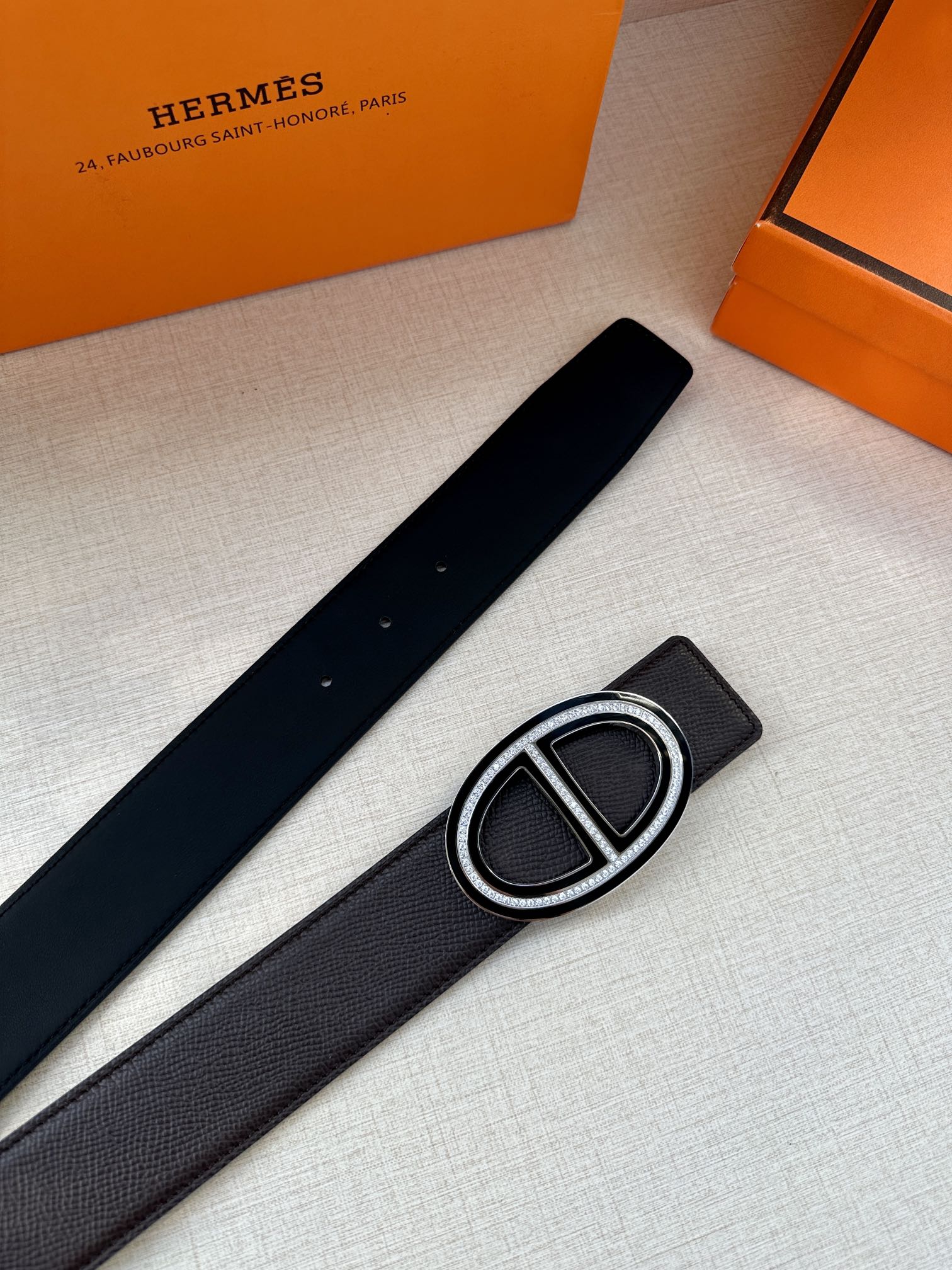 Black belt with textured strap and silver double-H buckle, side view