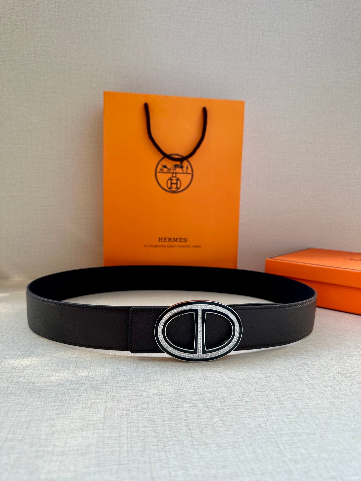 Hermes black leather belt with oval Double H buckle, front view on surface