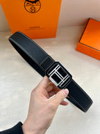 Dark leather belt with square silver-tone buckle and contrast white stitching.