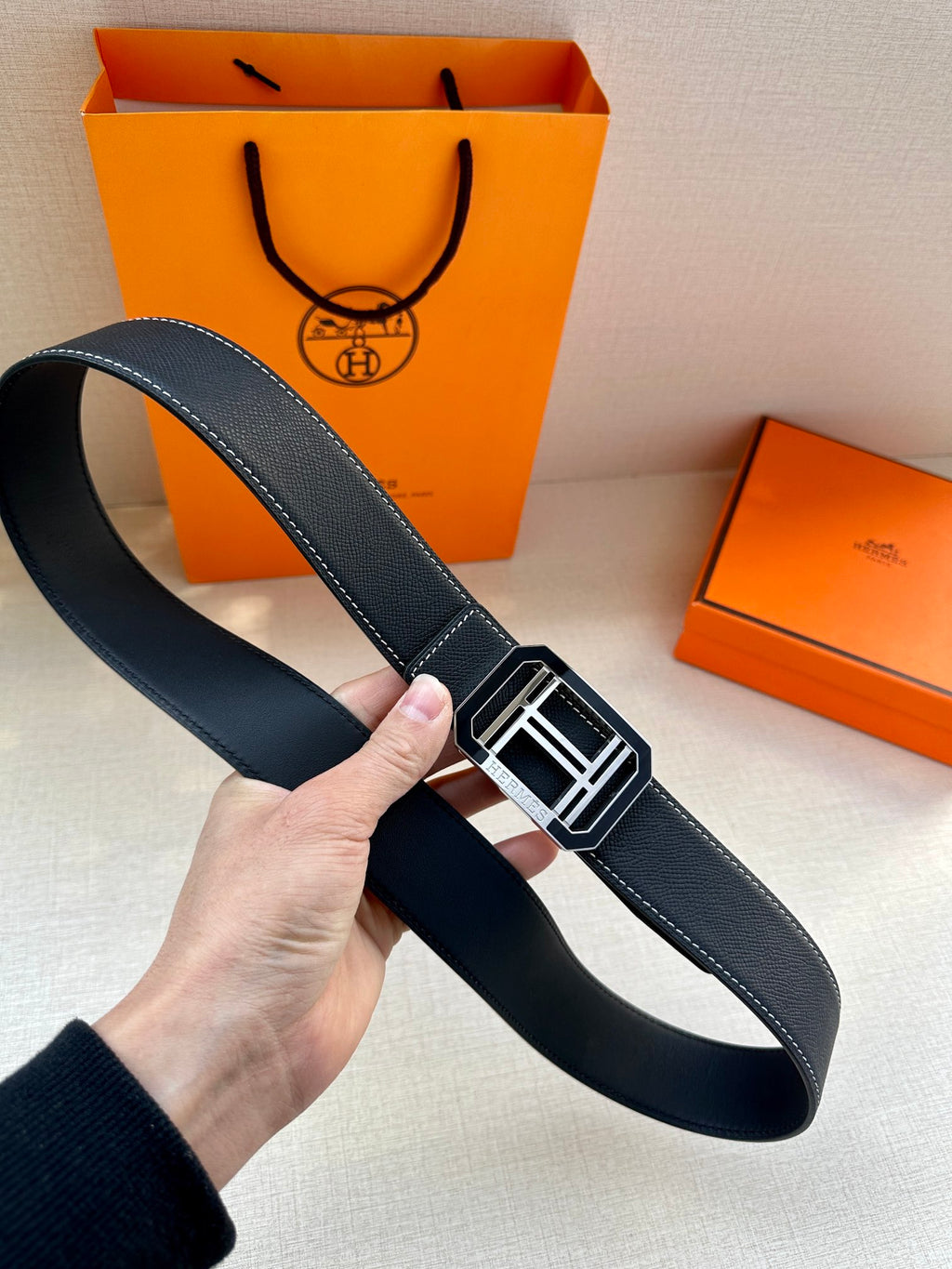 Dark leather belt with wide strap and silver-tone square buckle, viewed from side.