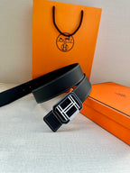 Dark leather belt with silver-tone square buckle and white contrast stitching, angled.