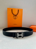 Dark leather belt laid flat with silver-tone square buckle at the center.
