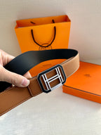 Tan leather belt with black lining and silver-tone square H buckle close-up