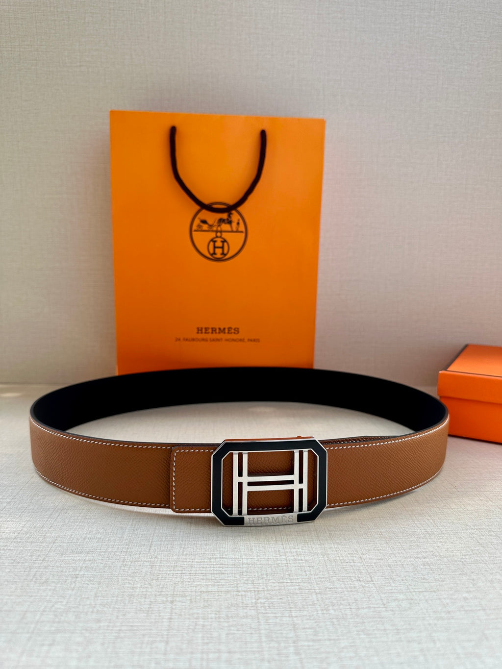 Tan leather belt with silver square H buckle and black underside
