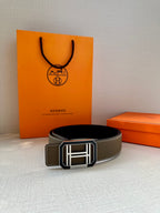 Dark gray leather belt with silver Hermes buckle, laid flat