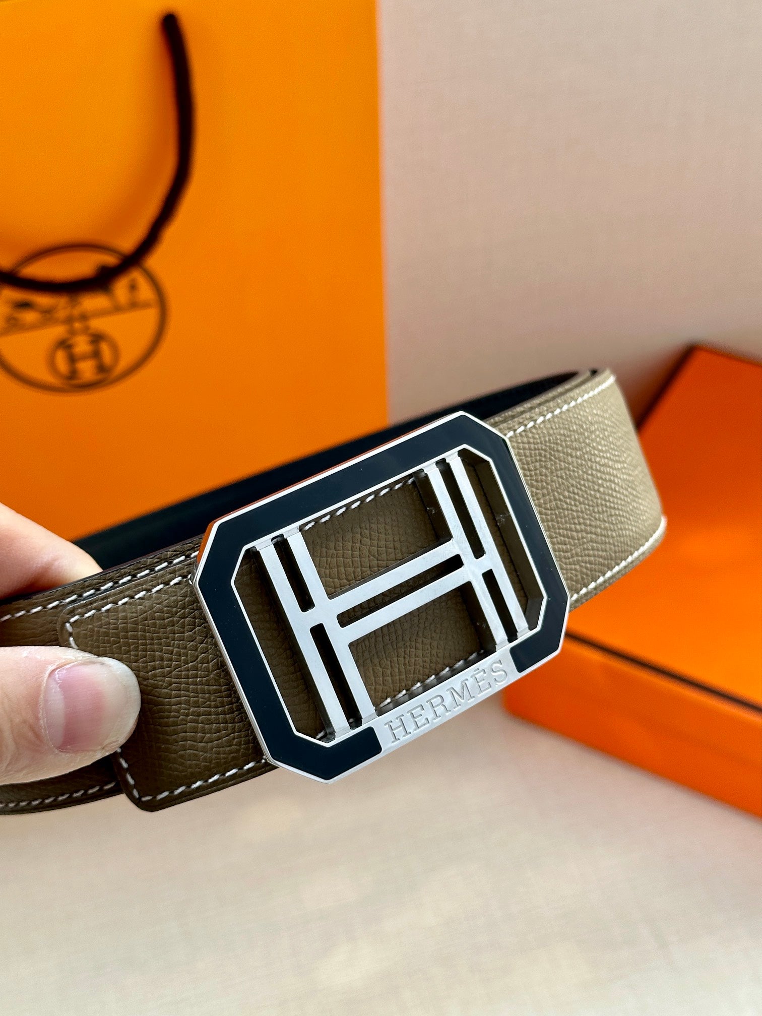 Dark gray leather belt with large silver Hermes buckle close-up
